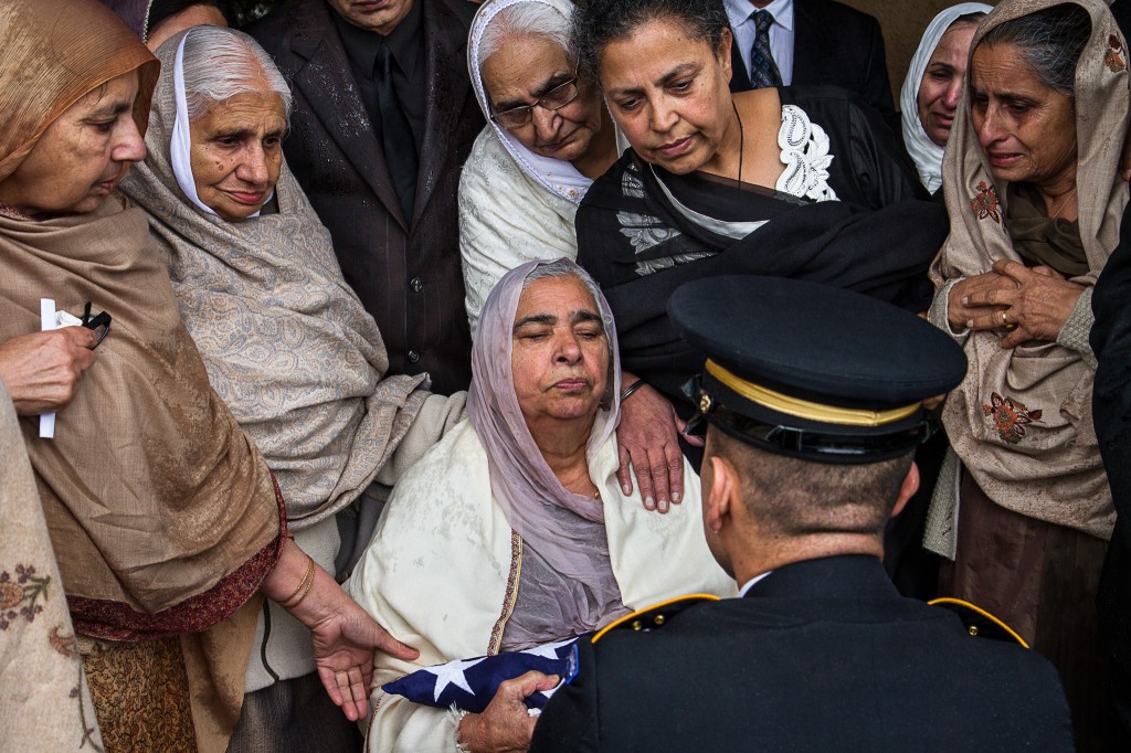 A military honor guard presents Sukhwinder Kaur with the American flag that had draped the coffin of her son. 
