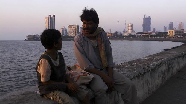 Rajesh Tailang as Mahendra Saini speaks with a child at the Sea Wall in Mumbai in SIDDHARTH. A film by Richie Mehta. A Zeitgeist Films release.